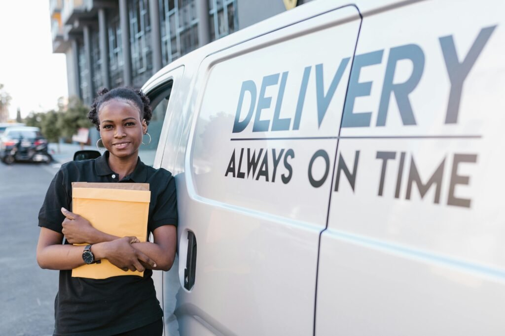 Smiling delivery woman with envelope by van, showcasing prompt service.